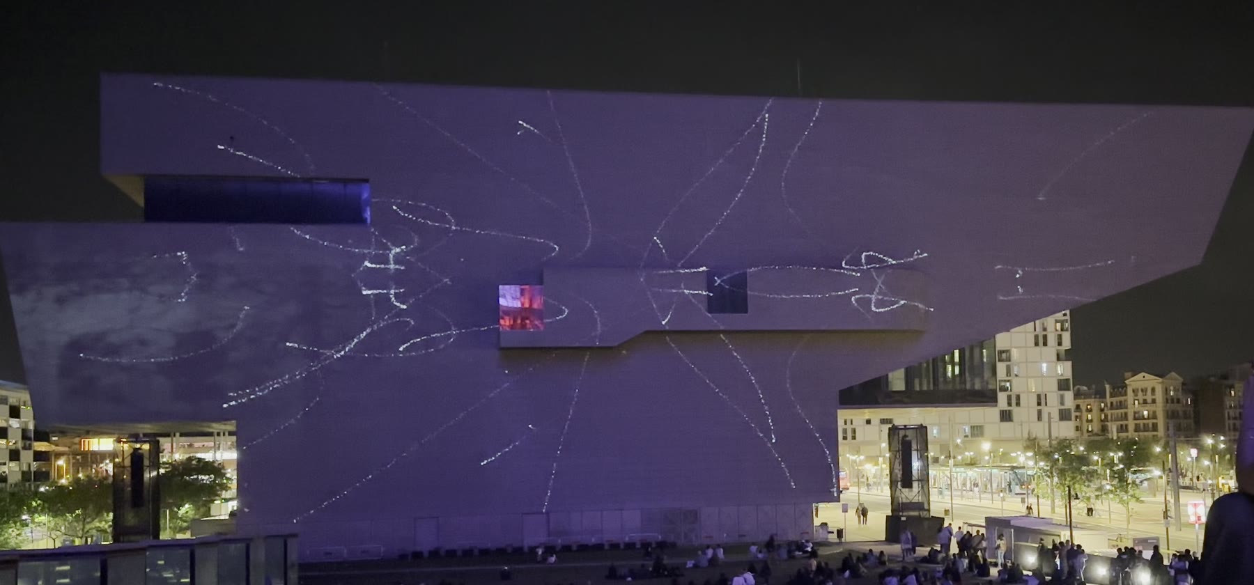 EMPREMTA — second phase. The silver chalk-like marks have multiplied across the facade, curling and branching outward in uneven handmade strokes.